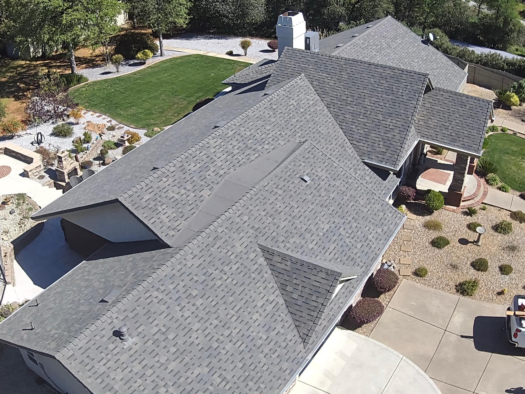 Aerial view of a large multi-hip shingle roof with a backyard patio