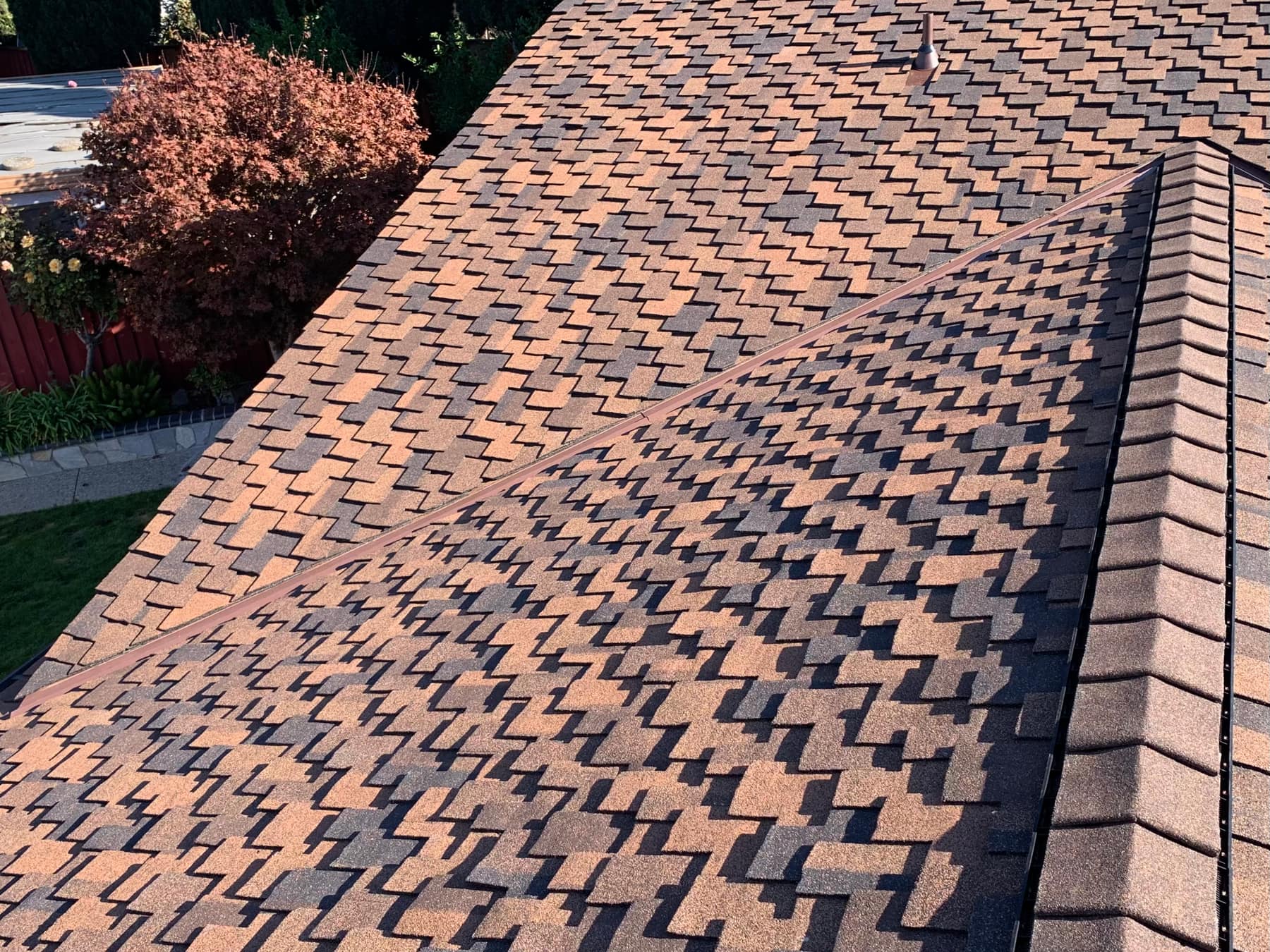 Aerial view of a finished shingle roof ridge line with a plumbing vent