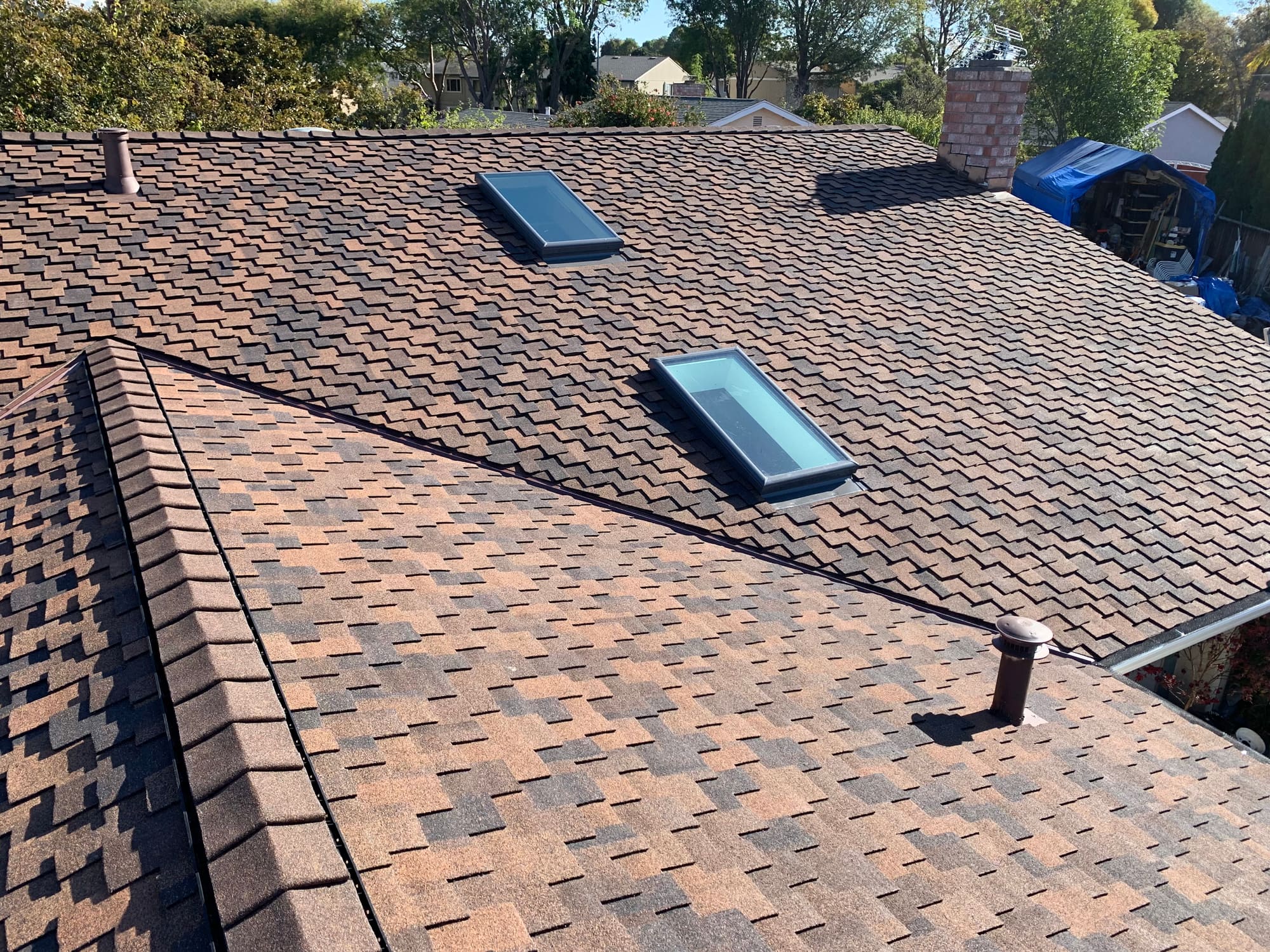 Close-up of shingle roof with skylights and brick chimney flashing