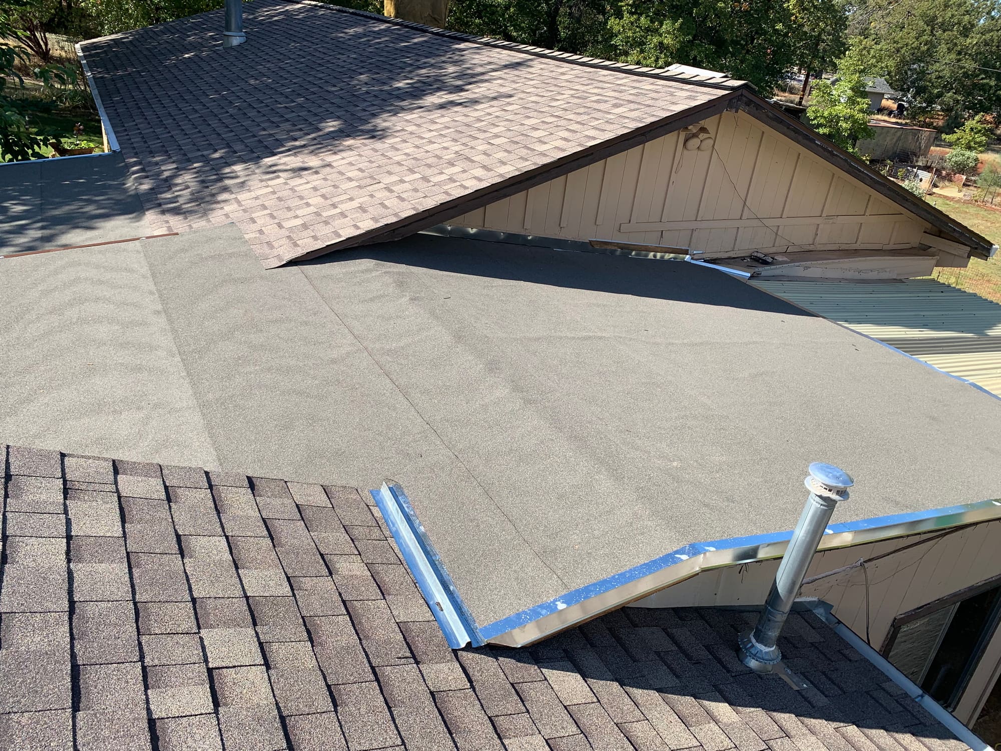Finished low-slope roof section with metal drip edge, viewed from a dormer