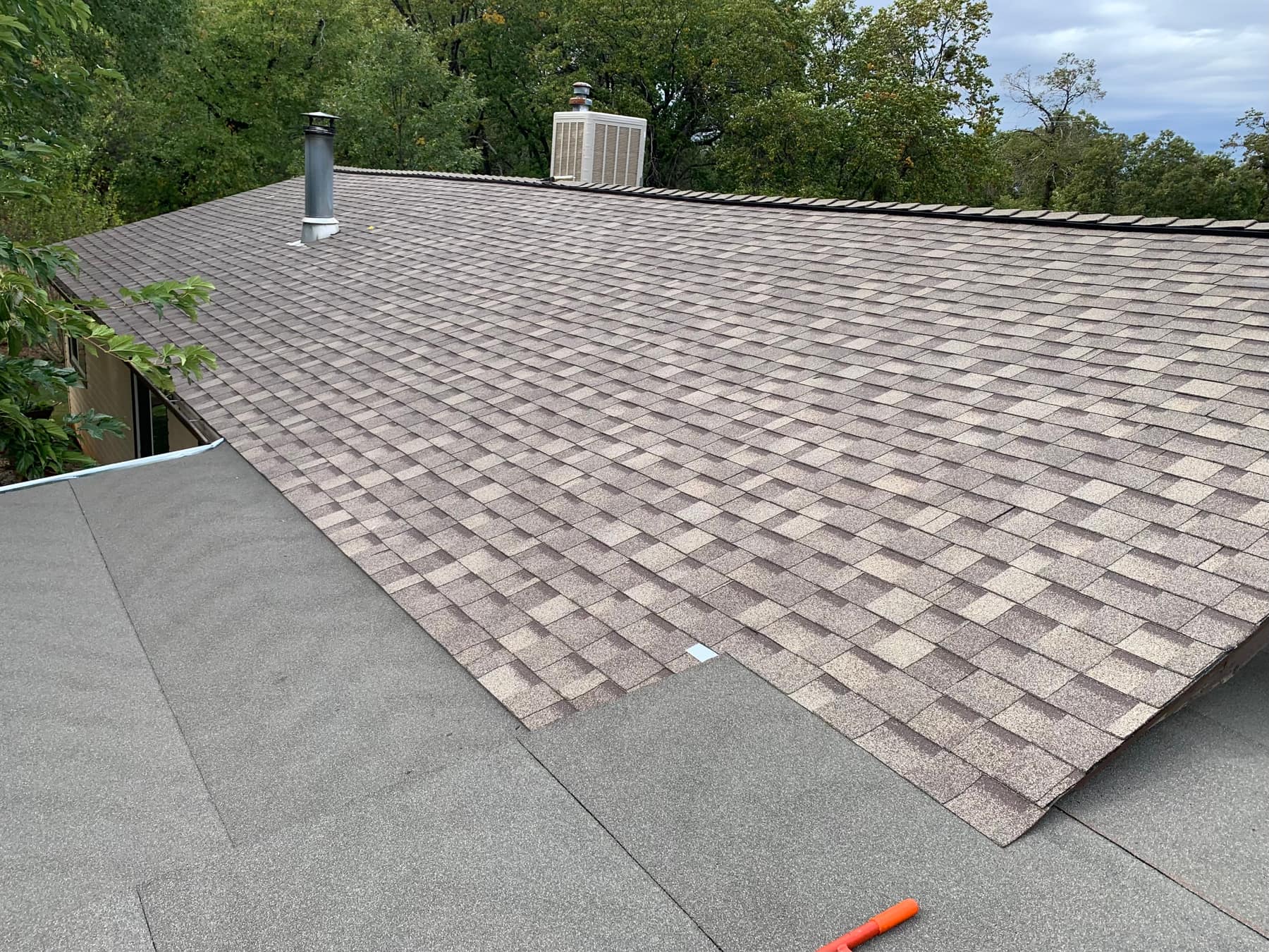 Roof mid-tear-off showing old roofing material next to newly installed shingles