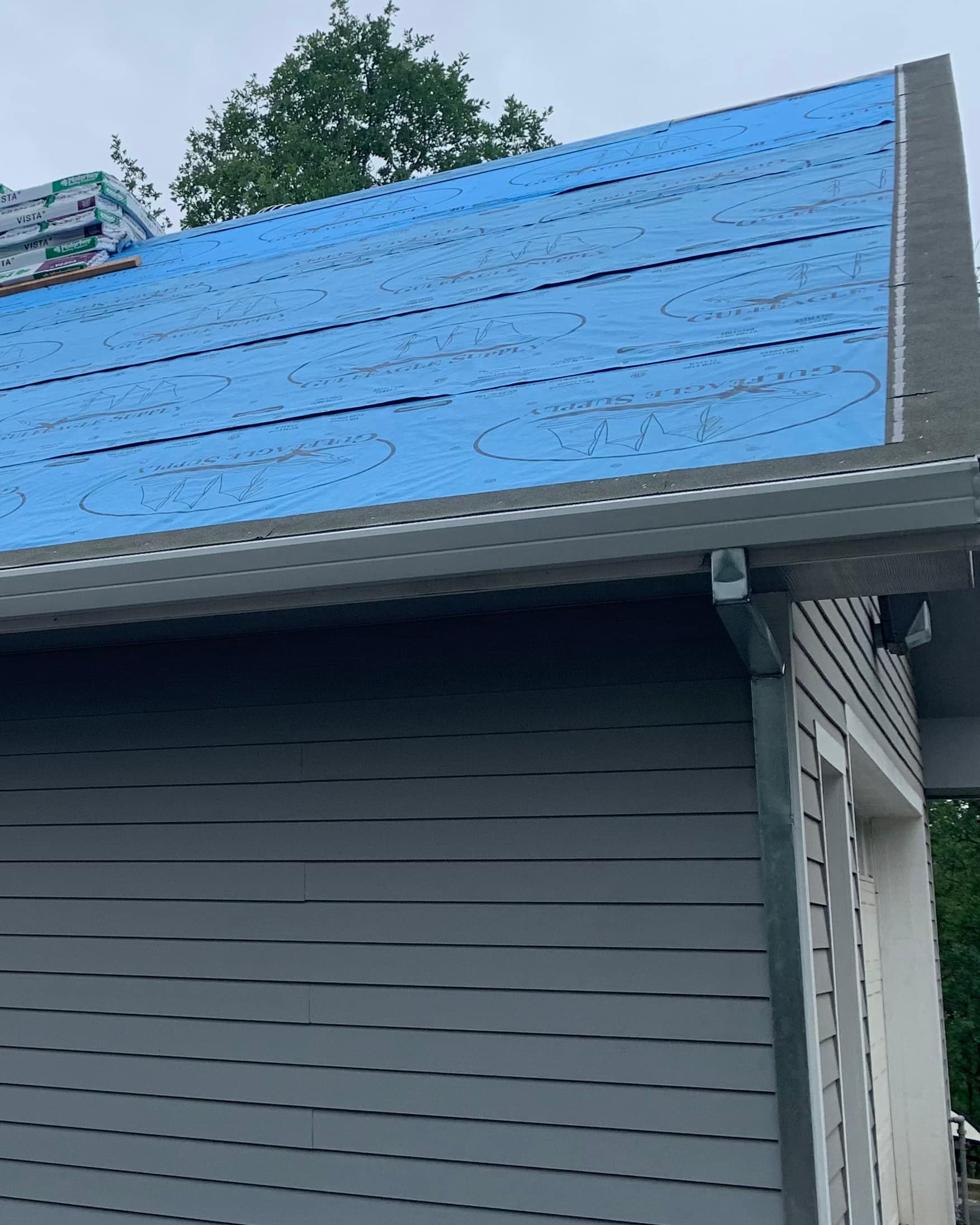 Synthetic underlayment installed on a roof deck ahead of the shingles